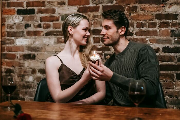 A couple celebrating with a cupcake, looking at each other. They found some worst things on partners phone.