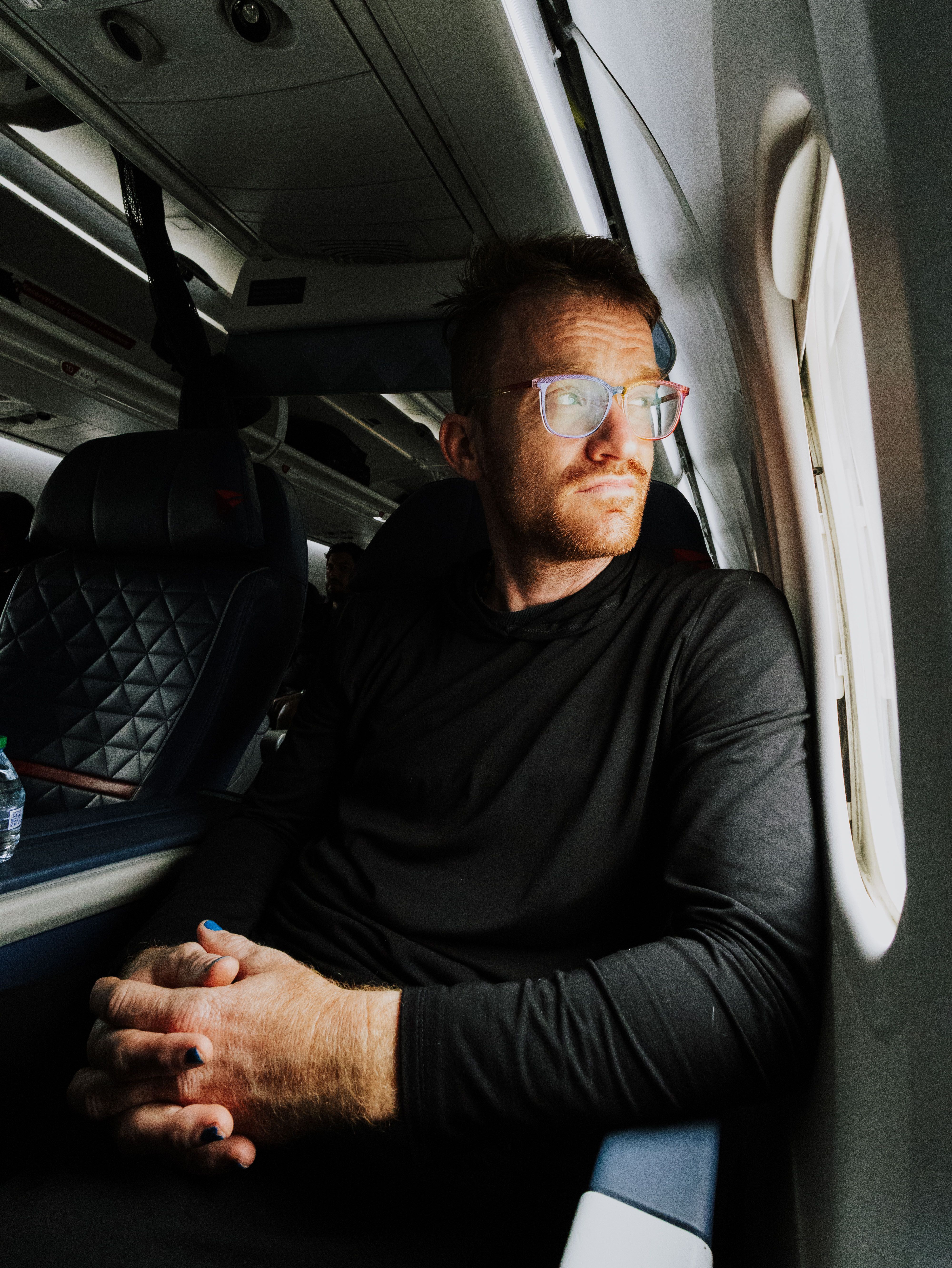 Man on airplane looking out window, involved in airport physical altercation after entering wrong line. Man on airplane looking out window, involved in airport physical altercation after entering wrong line.