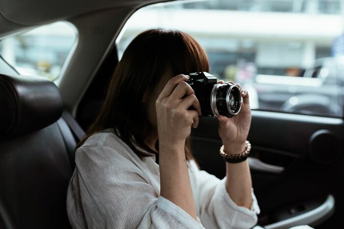 Woman taking photo with camera while sitting in car