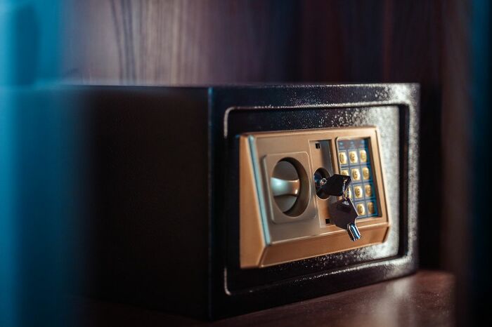 A closed black and gold safe with a key in the lock and a keypad, indicating experiences people can't explain.