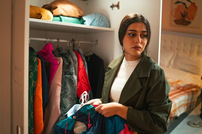 A woman looking troubled while holding clothes, experiencing something creepy.