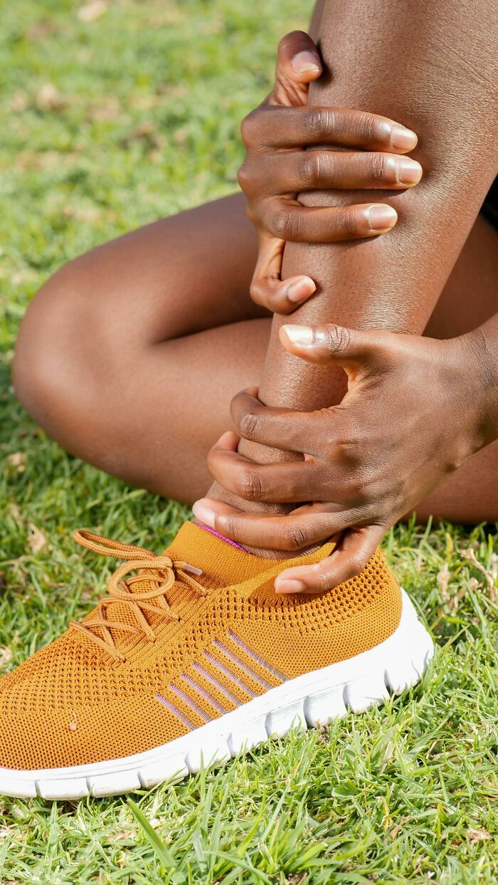 Person holding painful ankle on grass showing injury and discomfort