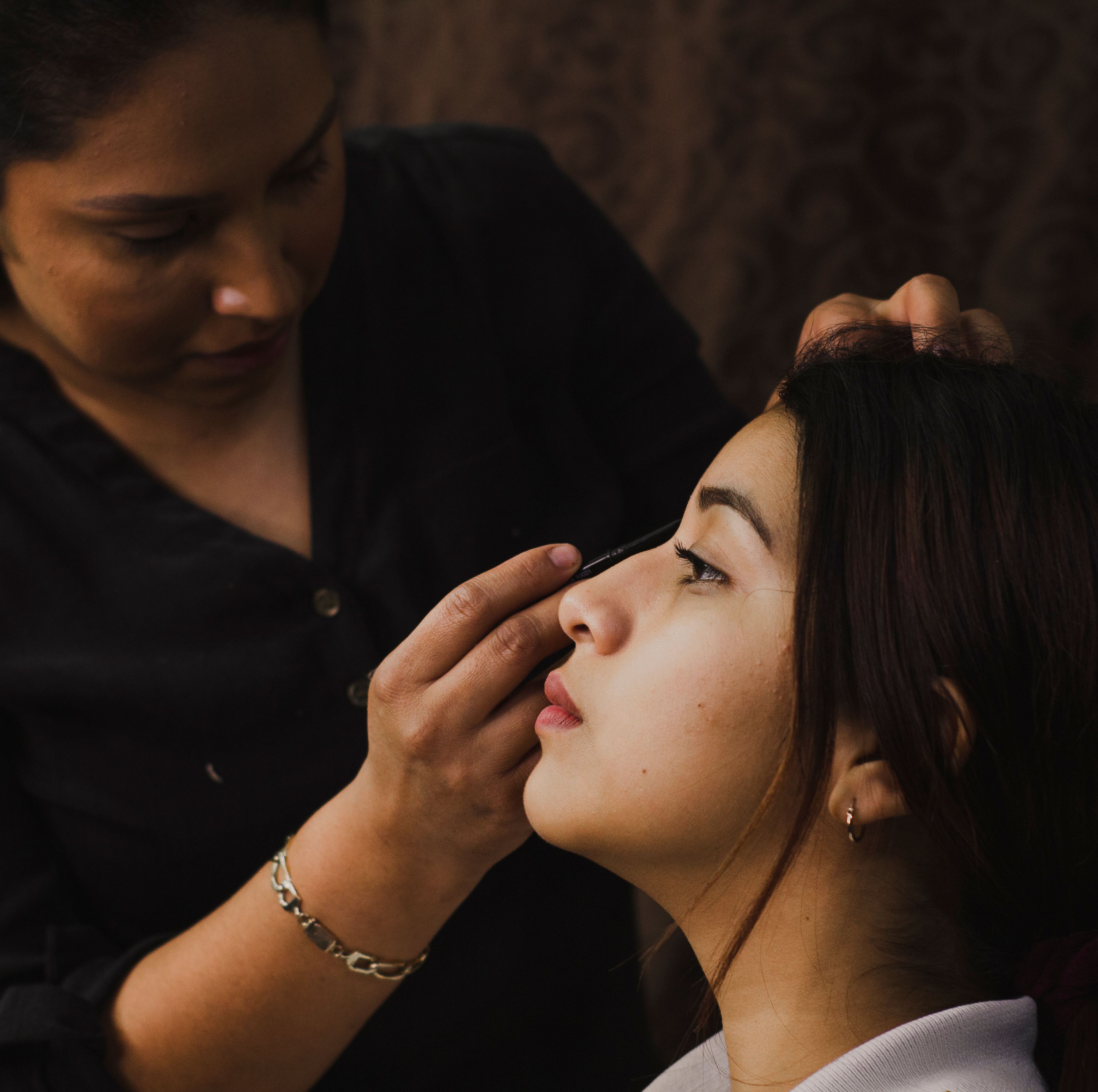 Makeup artist applying eyeliner to bride before ceremony