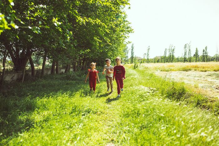 Children running along green path under sunlight