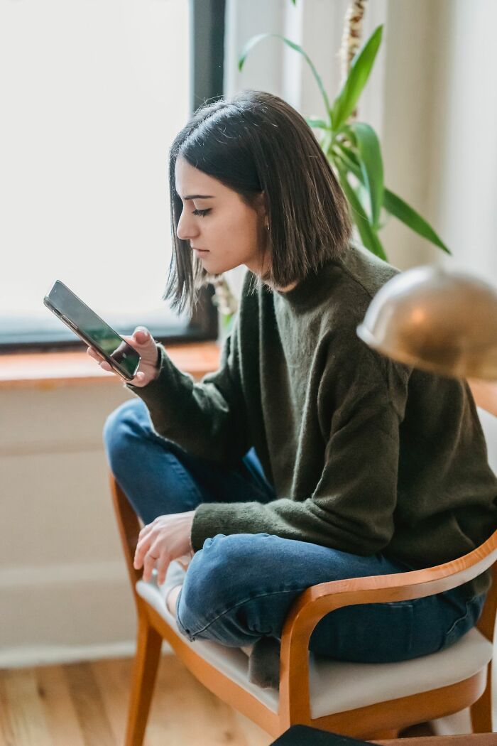 A woman sitting with a phone, illustrating the worst things people found on partners phone.