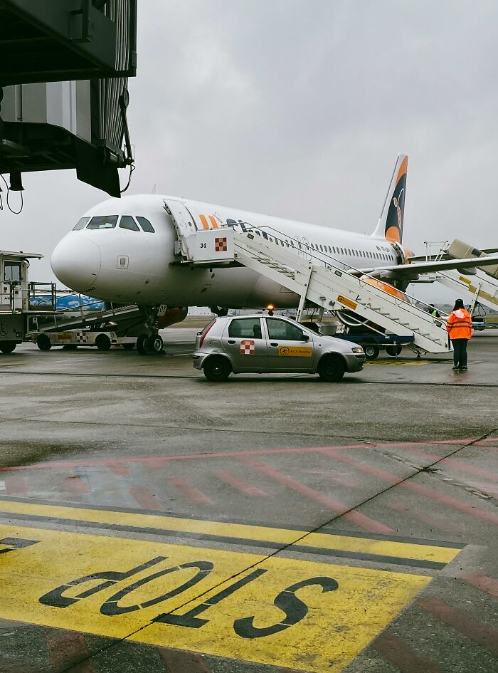 Airplane parked at gate with boarding stairs and airport staff