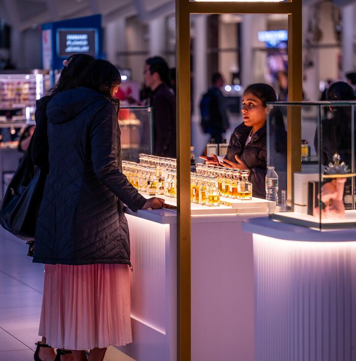 A woman browsing perfumes at a counter, experiencing a wild coincidence.