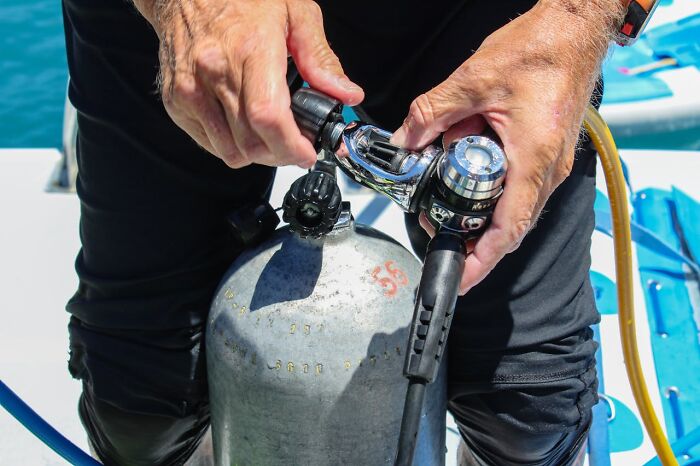 Person preparing scuba diving gear on boat deck