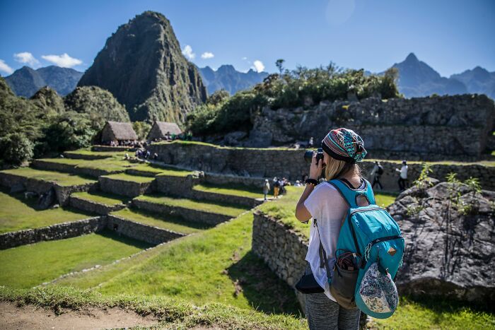 A person with a backpack taking a photo of ancient ruins, possibly encountering incredible coincidences.