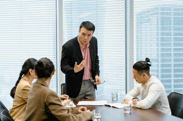 A secretly smart man leading a meeting, displaying hints of strong leadership and intellectual capacity.
