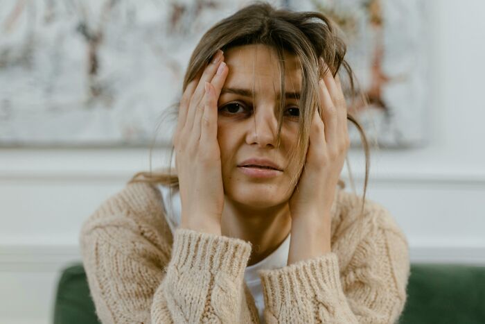 Stressed woman holding her face indoors