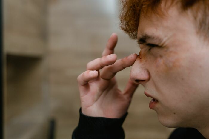 A young person with red hair looking distressed, touching their face, depicting an experience during an ER visit.