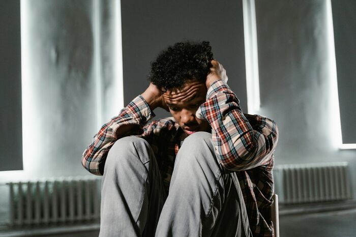 A man holding his head in distress, symbolizing the unsettling feeling of a bed compressing.