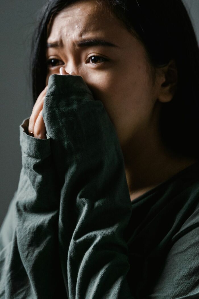 Close up of anxious woman covering face with sweater sleeve