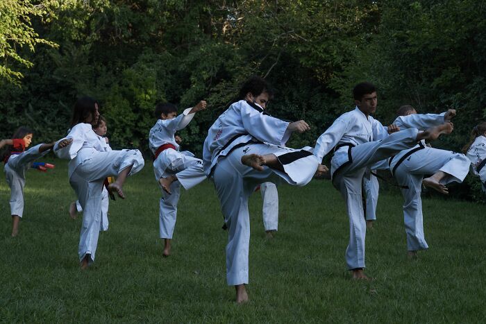 A group of people performing a martial arts kick outdoors, embodying a rage mode.