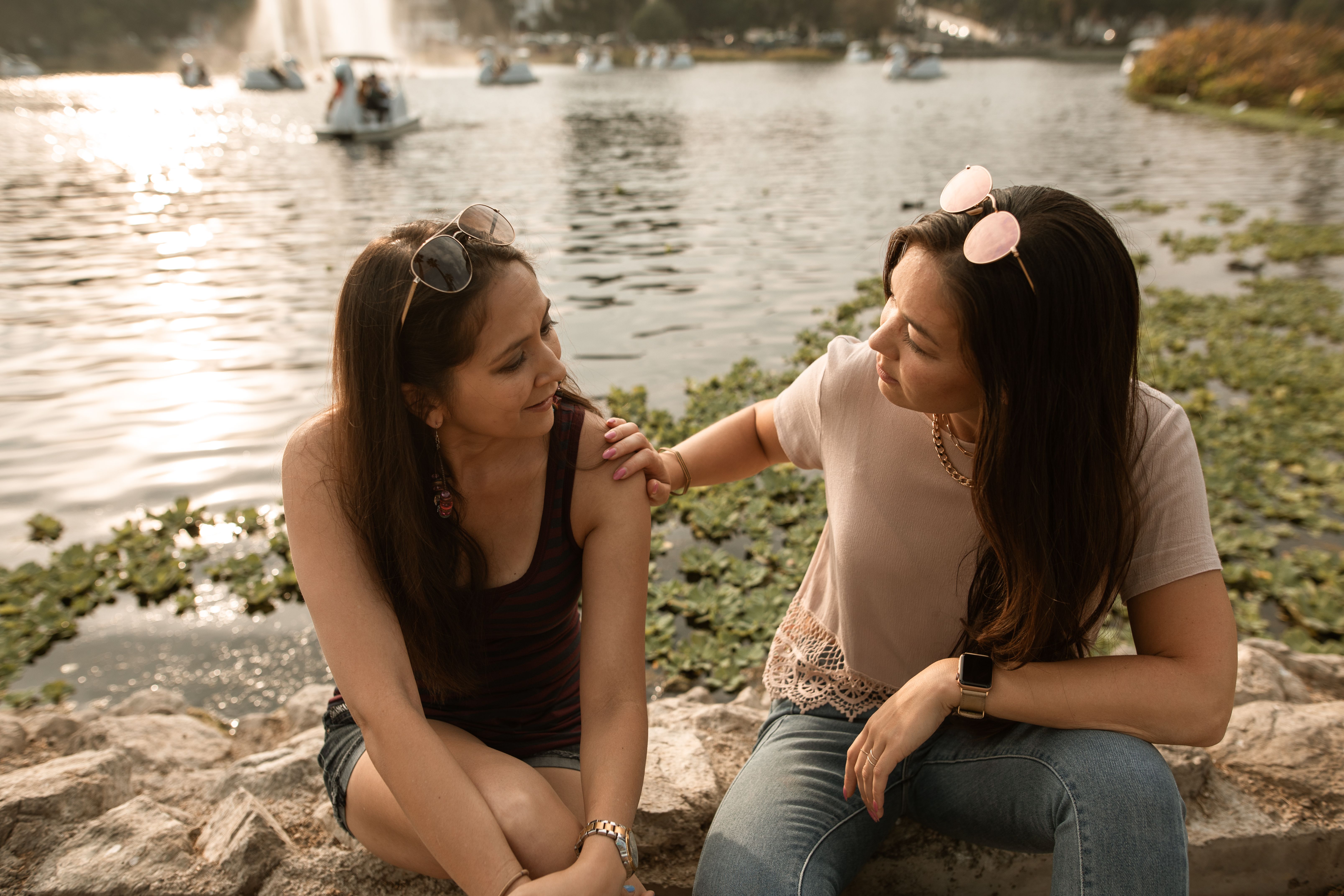Two women by a lake, one comforting the other, after an ex tries to embarrass a woman.