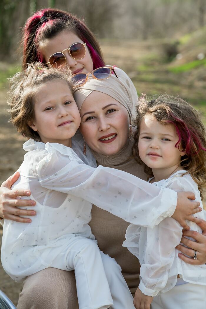A mother and her three daughters smiling together outdoors, depicting dynamics within polygamist families.
