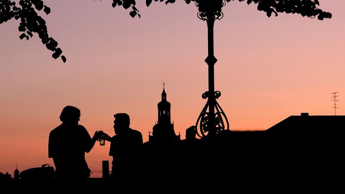 Silhouette of movie characters against an orange and pink sunset with a tall, ornate lamp post and distant steeple. Silhouette of movie characters against an orange and pink sunset with a tall, ornate lamp post and distant steeple.