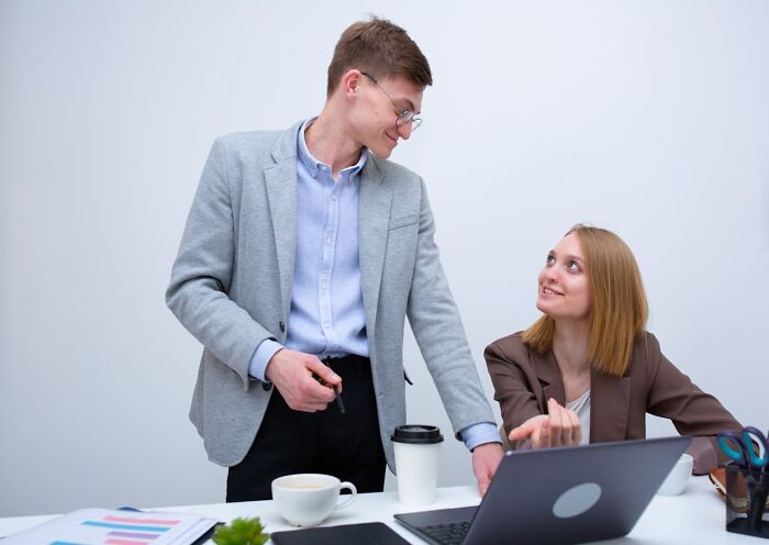 Man and woman working together with laptop showing surprising partner phone findings