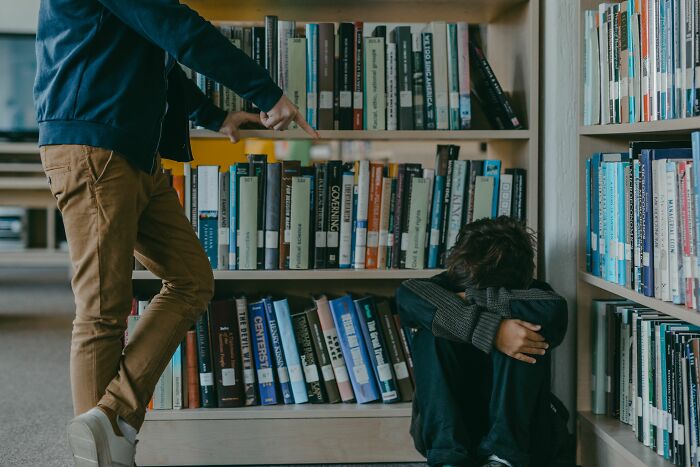 Someone pointing at a person curled up on the floor in a library, depicting a moment people snapped and went full rage mode.