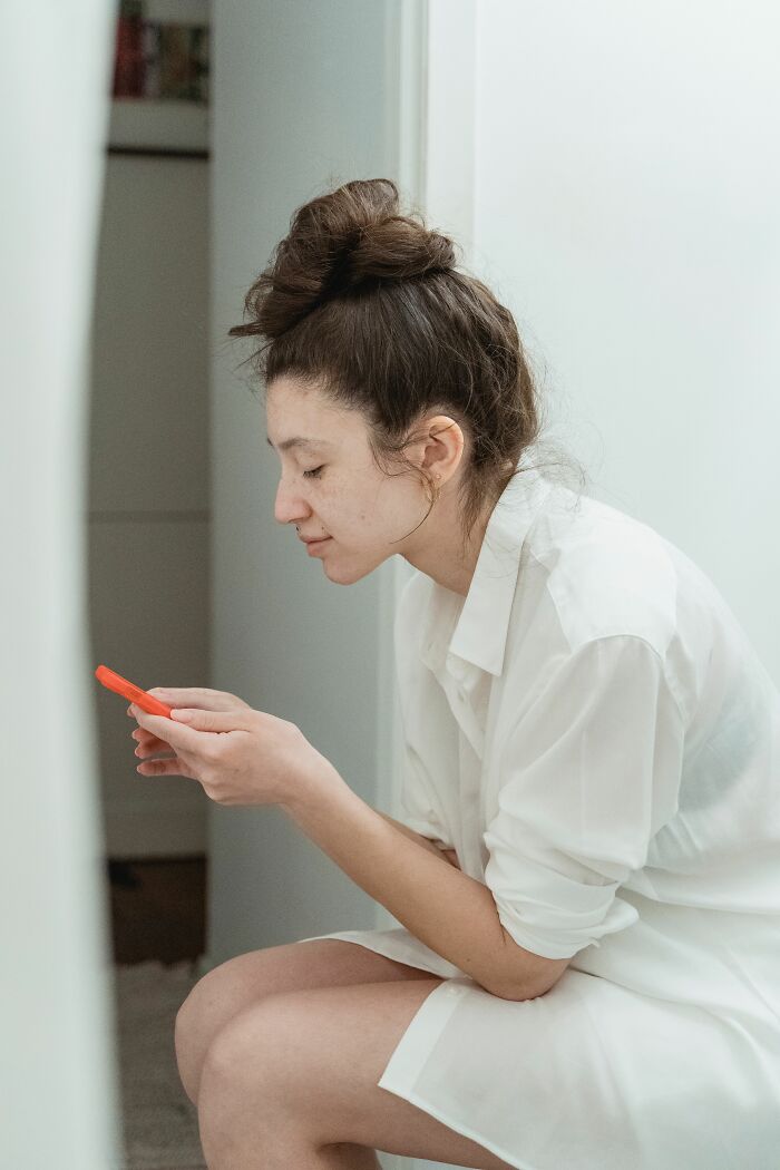 A woman with hair tied up, looking at her phone. Discovering NSFW facts about human bodies.
