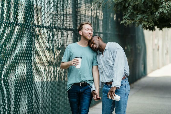 Two men enjoying walk together holding hands and coffee cups