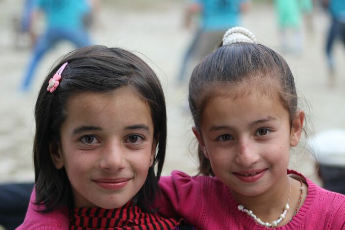 Two young girls smiling, one with an arm around the other, showing a heartwarming instance of wild coincidences.
