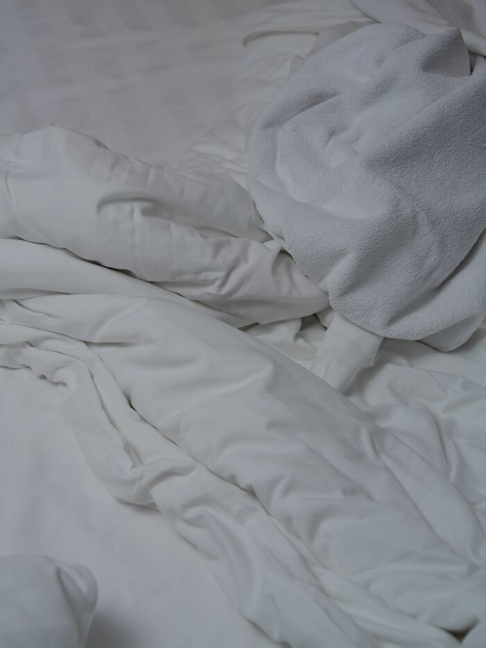 Disheveled white bedding and towel, symbolizing a common aspect of human bodies and daily life.