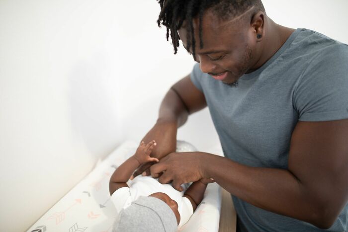 Father changing newborn baby on a changing table with scientific questions theme