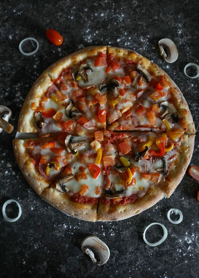 Vegetable pizza with mushrooms and bell peppers on dark surface