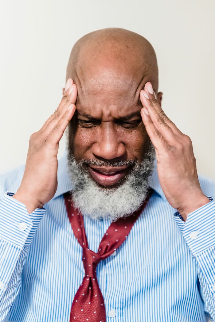 A man with his hands on his temples, expressing headache pain or mental anguish.