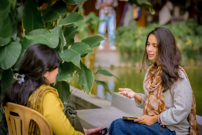 Two women talking in garden with greenery