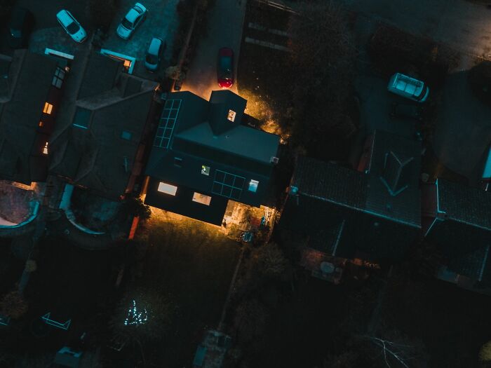 Aerial night view of illuminated house and parked cars