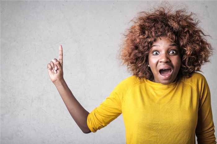 Surprised woman pointing upwards illustrating entitled parents shocked expression