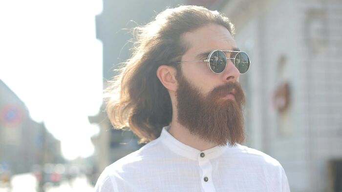 Man with long hair and full beard wearing round sunglasses outdoors for beard identification challenge