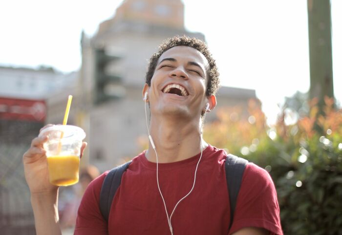 A man laughing and holding a drink, a hint that a person is secretly very smart with a cheerful outlook.