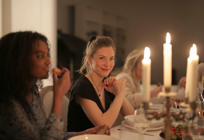 Women dining and chatting at a candlelit table during a gathering