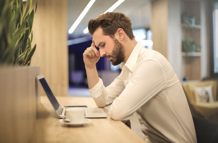 Stressed man working on laptop looking thoughtful and worried