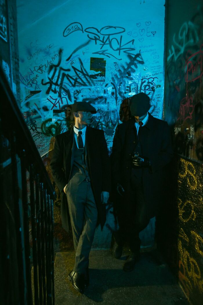 Two men in vintage suits walking in graffiti-covered stairwell at night