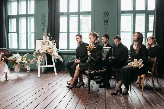 Mourners dressed in black at a funeral, highlighting social cues in a somber setting.