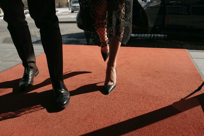 Close up of man and woman walking on red carpet in formal shoes