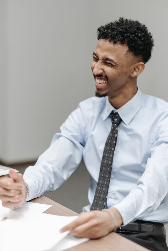 A man in a tie smiles and laughs, possibly in response to a wild courtroom story.