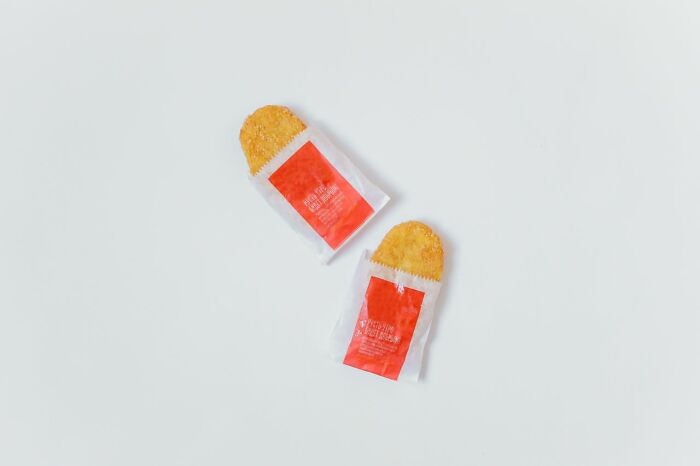 Two hash browns in paper bags on a white surface, potentially representing an unserious ER visit story.