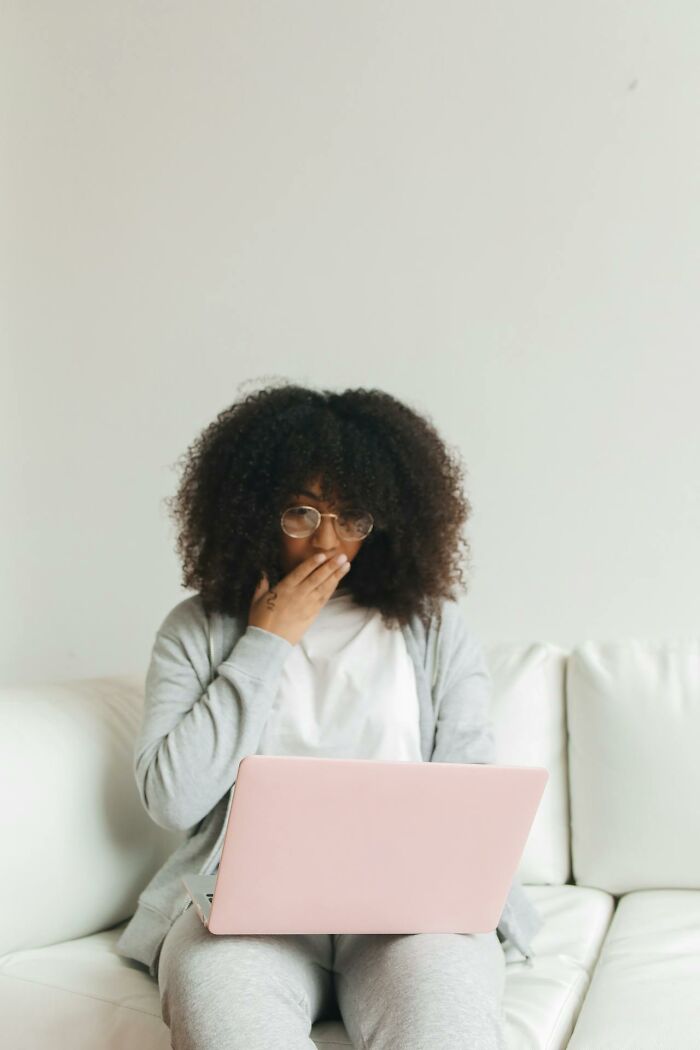 Surprised woman reading infidelity stories on laptop at home
