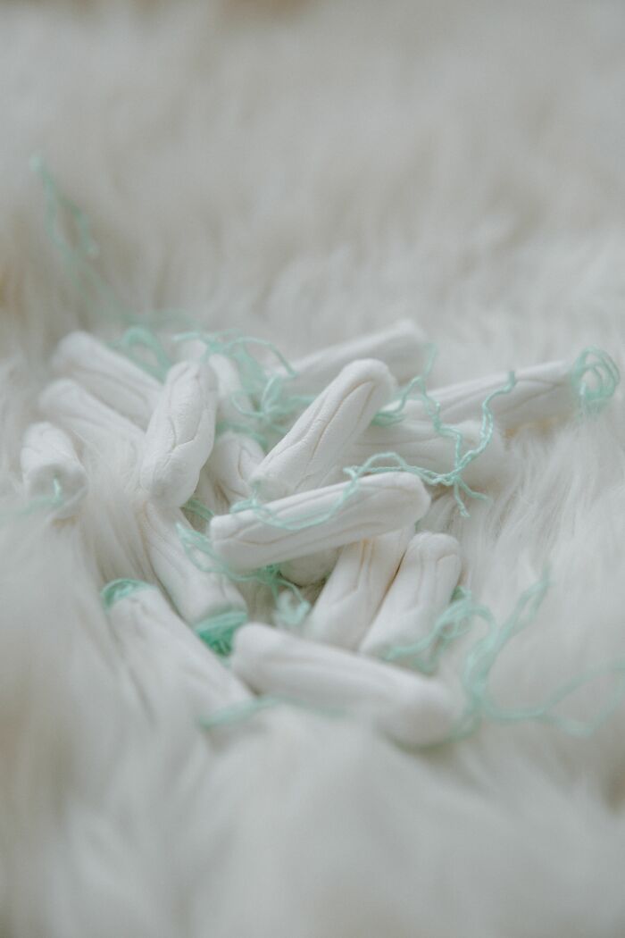 Pile of tampons with light green strings on a white furry surface, depicting facts about human bodies.