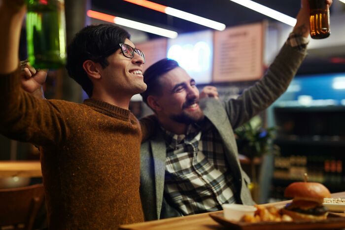 Friends raising drinks and smiling in a pub setting