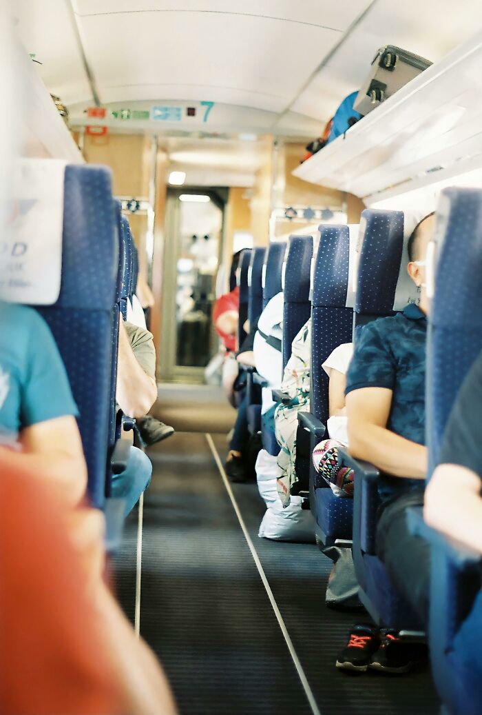 Inside view of crowded plane cabin aisle with passengers seated
