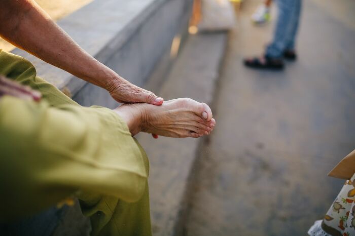 An older person massages their foot, dealing with types of pain they won't comprehend.