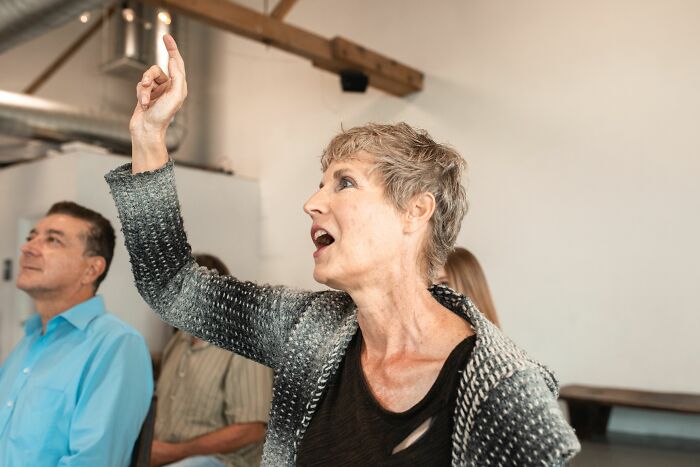 Woman raising hand in discussion, representing British humor