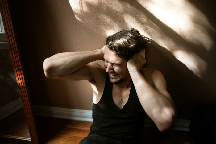 Stressed man holding his head sitting on the floor indoors